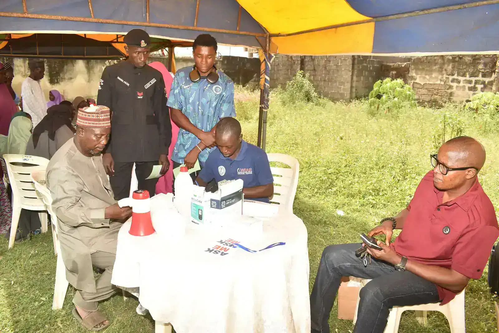 People gathered around a table with health-check equipment at a community outreach