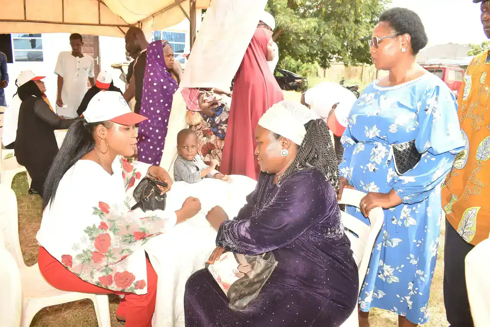 People in conversation under an outdoor tent at a community outreach