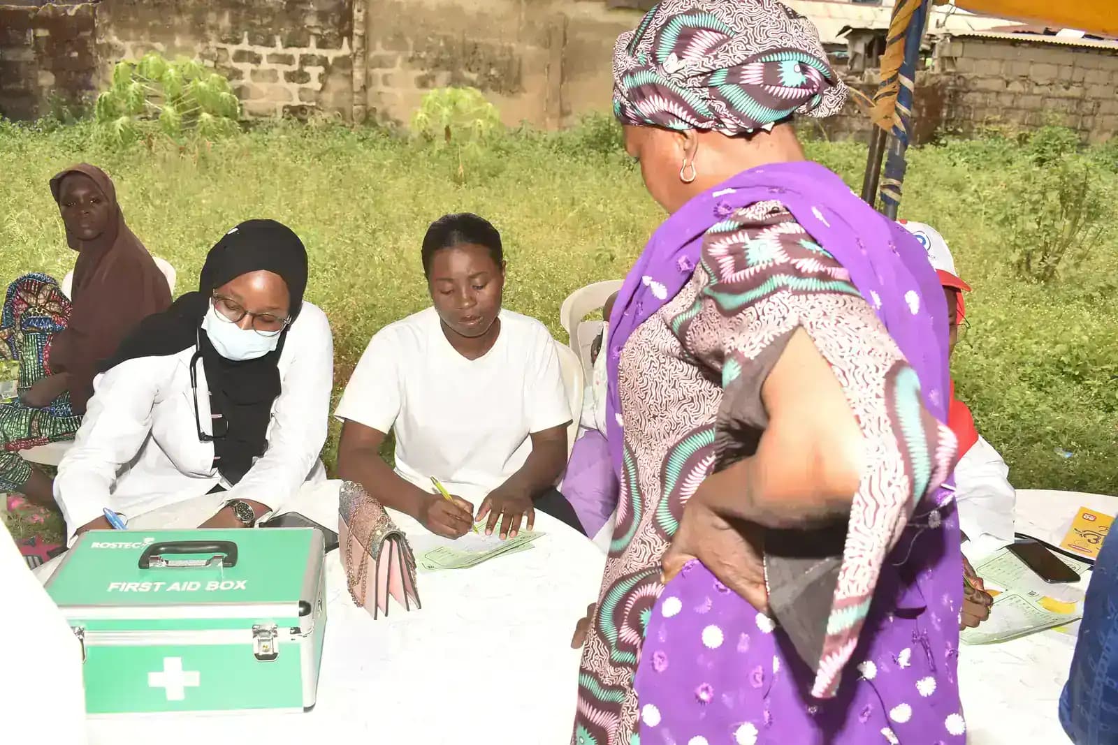 People seated at a community health table while a woman stands nearby